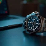 FintechZoom Rolex Submariner watch displaying iconic rotating bezel and luminescent markers on luxury investment desk setup