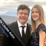 Portrait of Isabella Louise Astin smiling confidently against a soft, neutral background.