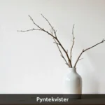 Pyntekvister decorative branches in glass vase on wooden table showing Scandinavian home decor styling