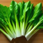 Fresh Yalla Choy vegetable with green leaves and yellow buds on white surface showing whole bunch and cut pieces ready for cooking