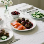 Bjudlunch table set with Swedish lunch dishes including meatballs, salmon, and bread for hosting guests