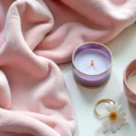Bougiebunna aesthetic flat lay with pastel pink blanket rose gold accessories and lavender candle on cream background