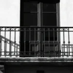 Mission Style Wrought Iron Balcony on Craftsman home exterior with vertical black pickets and top rail.