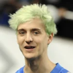 Who is Ninja streamer - Tyler Blevins wearing signature headband playing Fortnite on Twitch with gaming setup visible