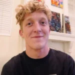 Who is Tfue - Professional gamer Turner Tenney at his streaming desk playing Fortnite with gaming headset and monitor.