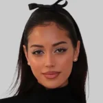 Who is Cindy Kimberly? Model Cindy Kimberly poses in a structured white LOBA corset top with flowing dark hair and minimal jewelry against a neutral backdrop.